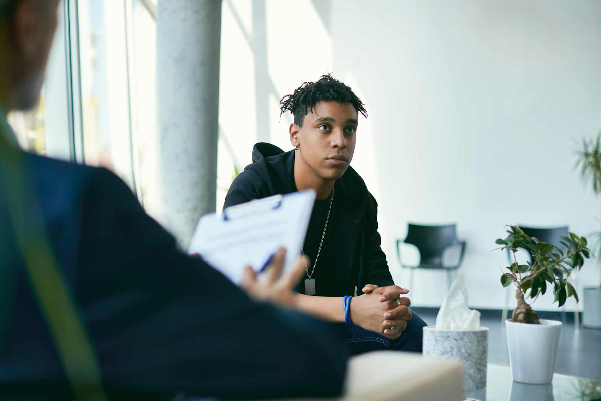 African American teenager having psychotherapy session at psychologist's office.