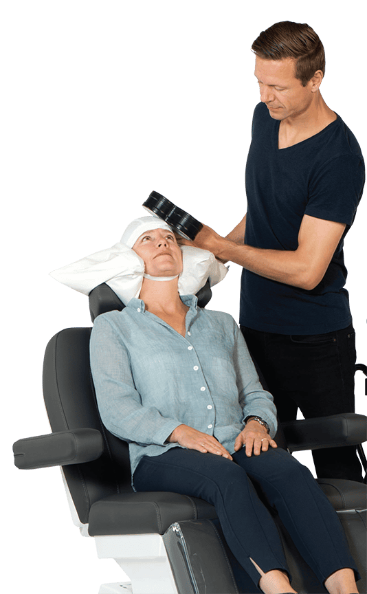 TMS provider administering treatment on a patient seated in a treatment chair.